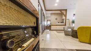 Een modern interieur met een vintage radio, een receptiebalie en een gele fauteuil.