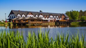Hotel aan het meer met meerdere bungalows op palen, een steiger en een restaurant.