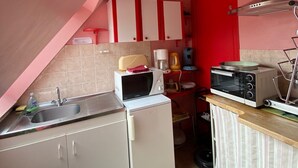 A compact kitchen with a sink, microwave, toaster, and a small refrigerator.
