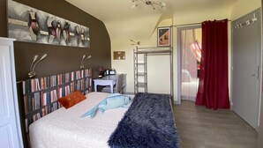 A bedroom with a bed, a desk, a bookshelf, a ladder, and a door.