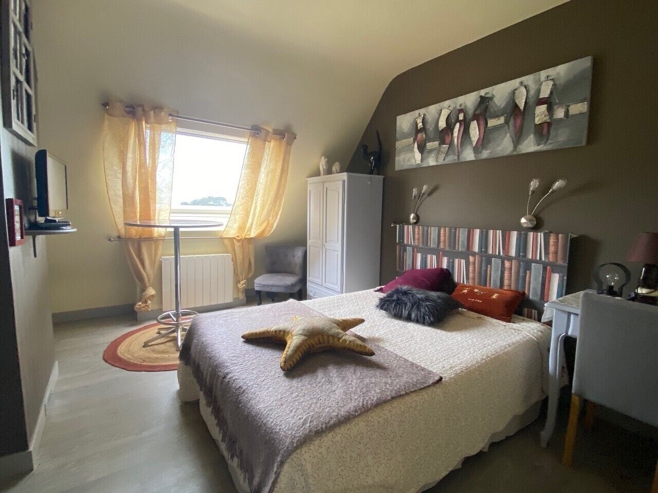 Een slaapkamer met een bed, een bureau, een stoel, een kledingkast en een raam met gordijnen.