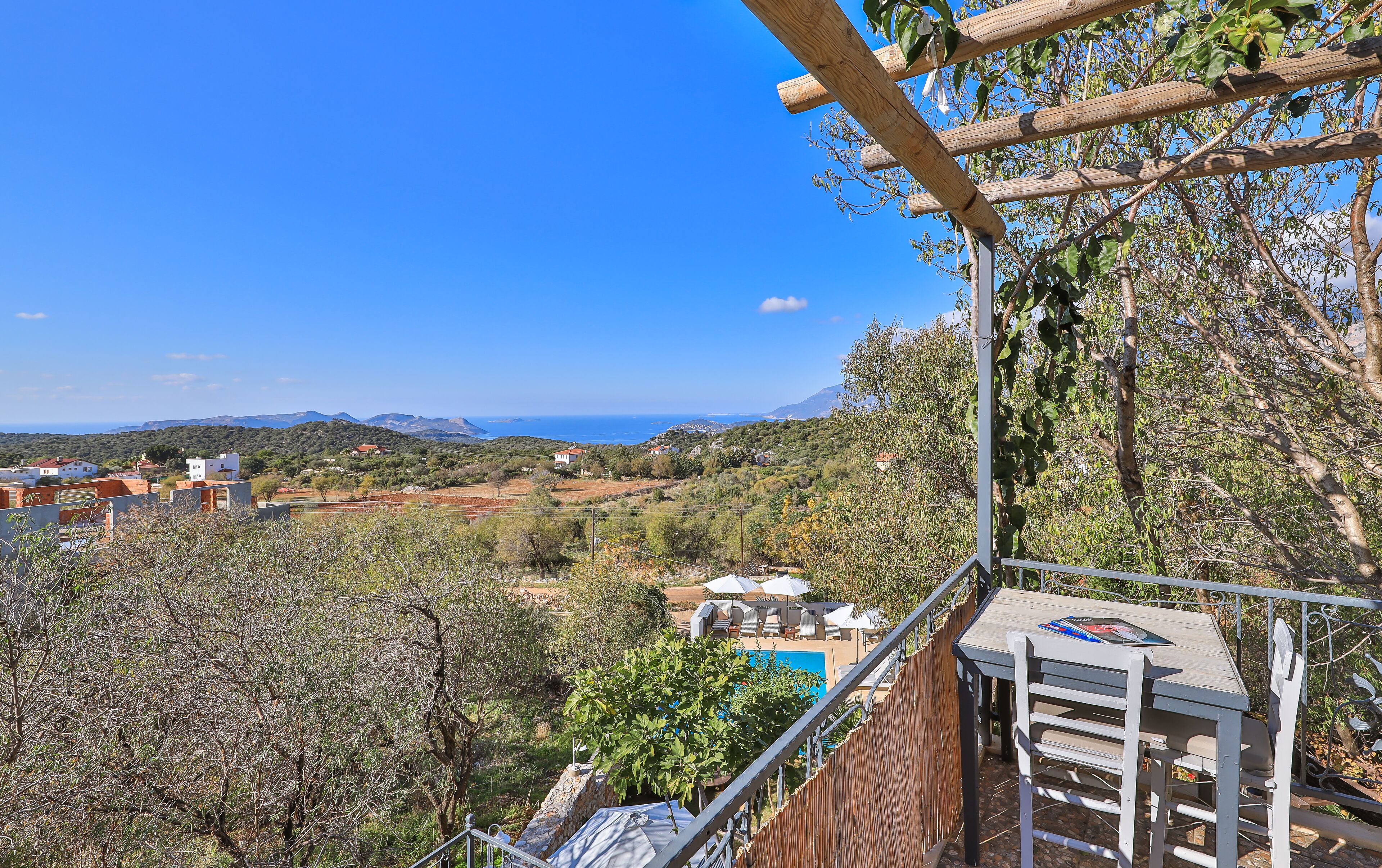 Eine Terrasse mit Blick auf einen Pool, umgeben von Bäumen und einer Berglandschaft.
