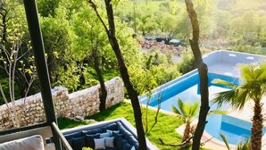 Un balcon avec un canapé, une table et une vue sur une piscine et un espace verdoyant.