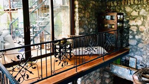 Un balcon avec des murs en pierre, une table en bois et une rambarde en métal.