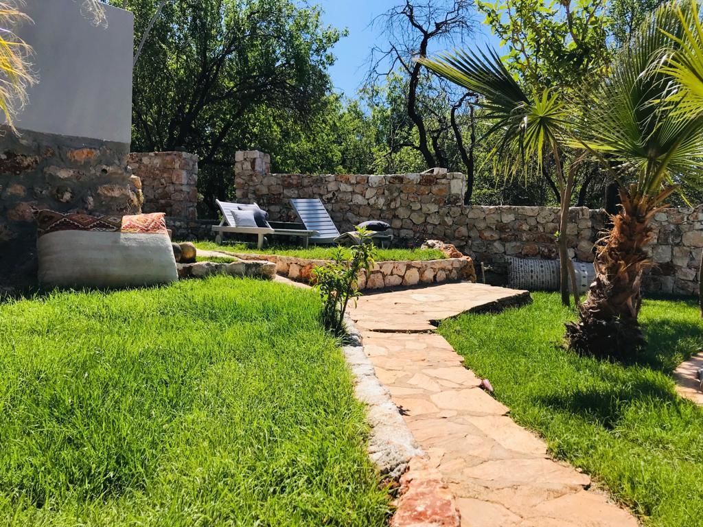Un vialetto in pietra conduce a un muro di pietra, con una poltrona da relax e un tavolino.