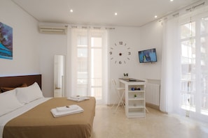 A hotel room with a bed, a desk, a TV, and a large window. - Toledo Stay OK (Naples)