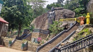 Una estatua grande de Buda sobre una montaña, con escaleras que suben hacia ella.