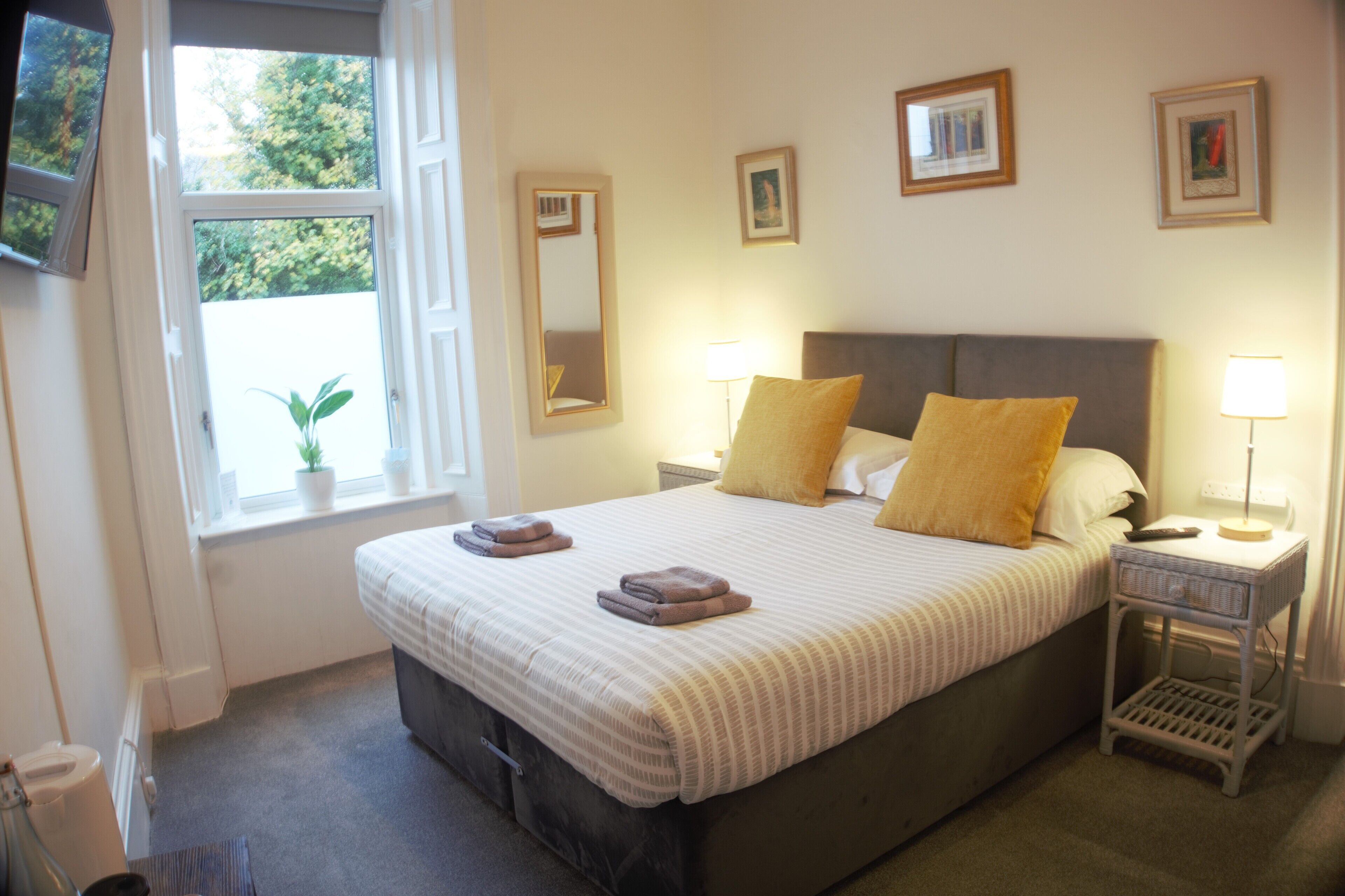 A neatly made bed with pillows and a bedside table with a lamp.