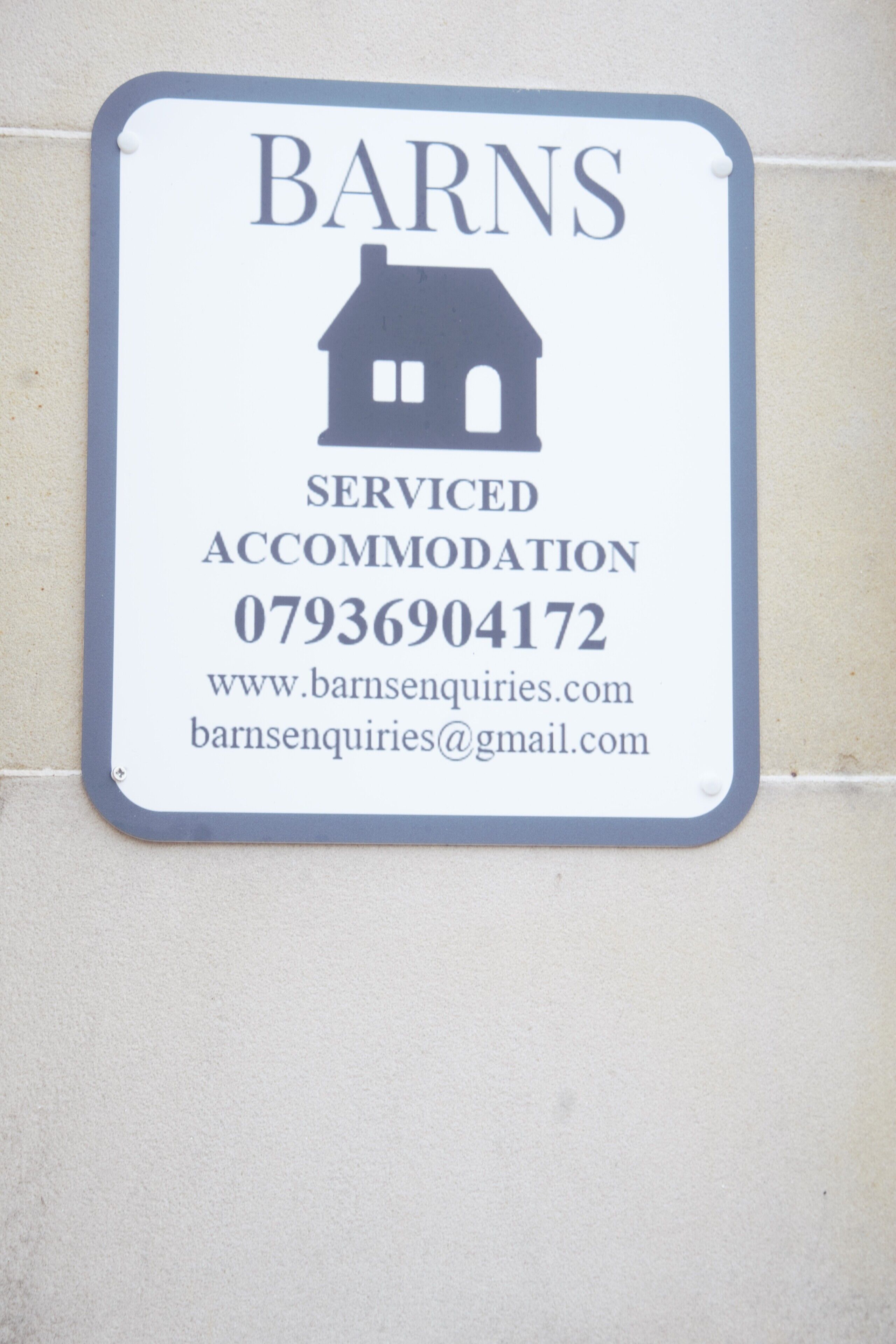 Une enseigne indiquant « Barns Serviced Accommodation » avec les coordonnées.