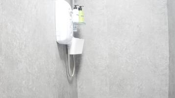 A shower with a handheld showerhead, a wall-mounted control panel, and a white sink with a mirror.