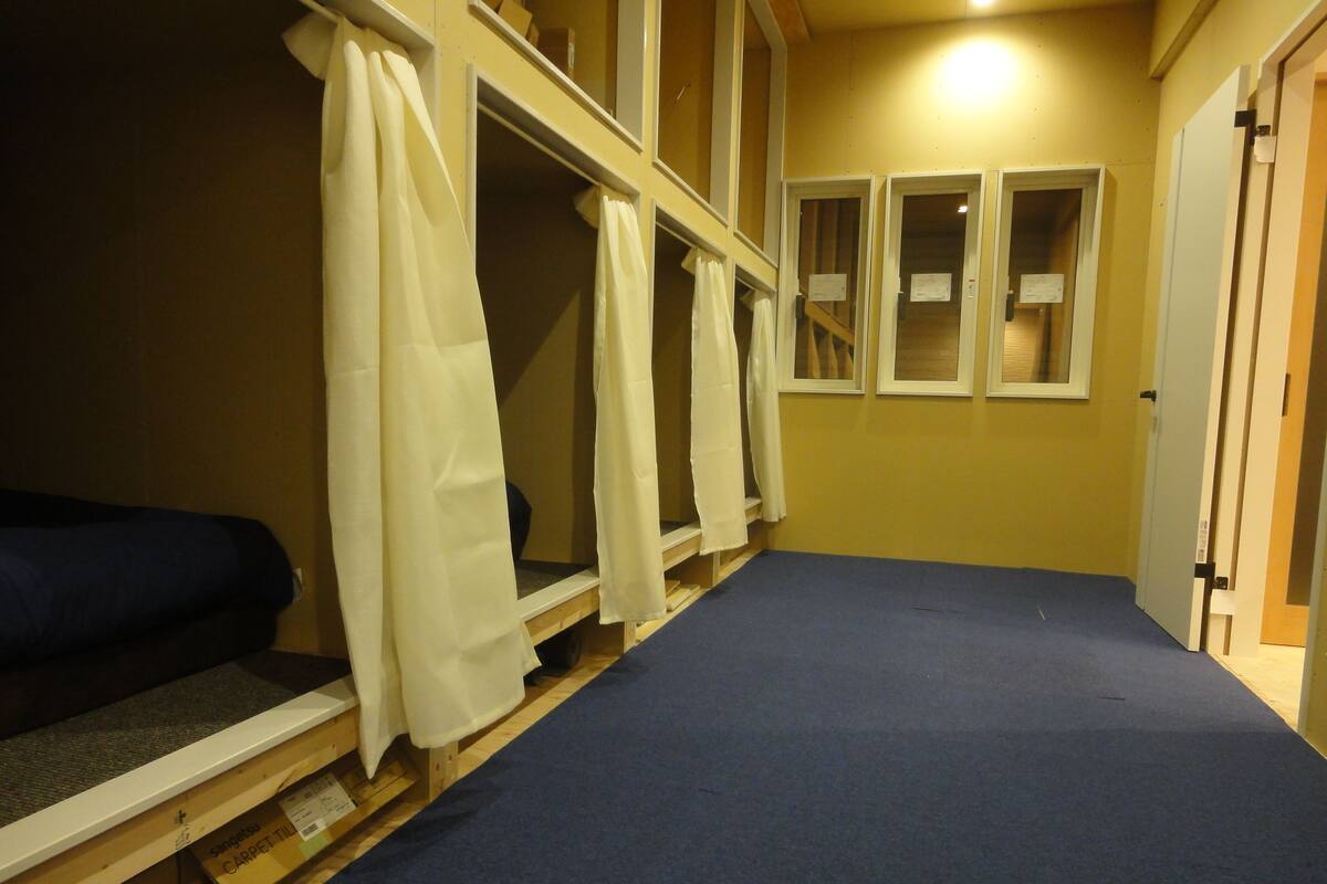Un passadís amb lliteres, bancs de fusta i una catifa blava.