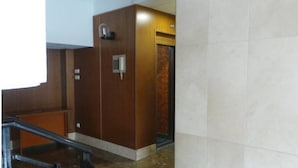 An elevator with a wooden finish and a metal handrail, leading to a door with a sign above it. - Floor 180 meters downtown area (Valencia)