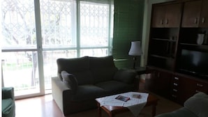 A living room with a sofa, a coffee table with magazines, a TV, and a cabinet. - Floor 180 meters downtown area (Valencia)