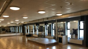 A spacious dance studio with wooden floors, large mirrors, and ceiling lights. - Hotell Gustaf (Götene)