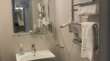 Casa de banho com lavatório, espelho, toalheiro e secador de cabelo.