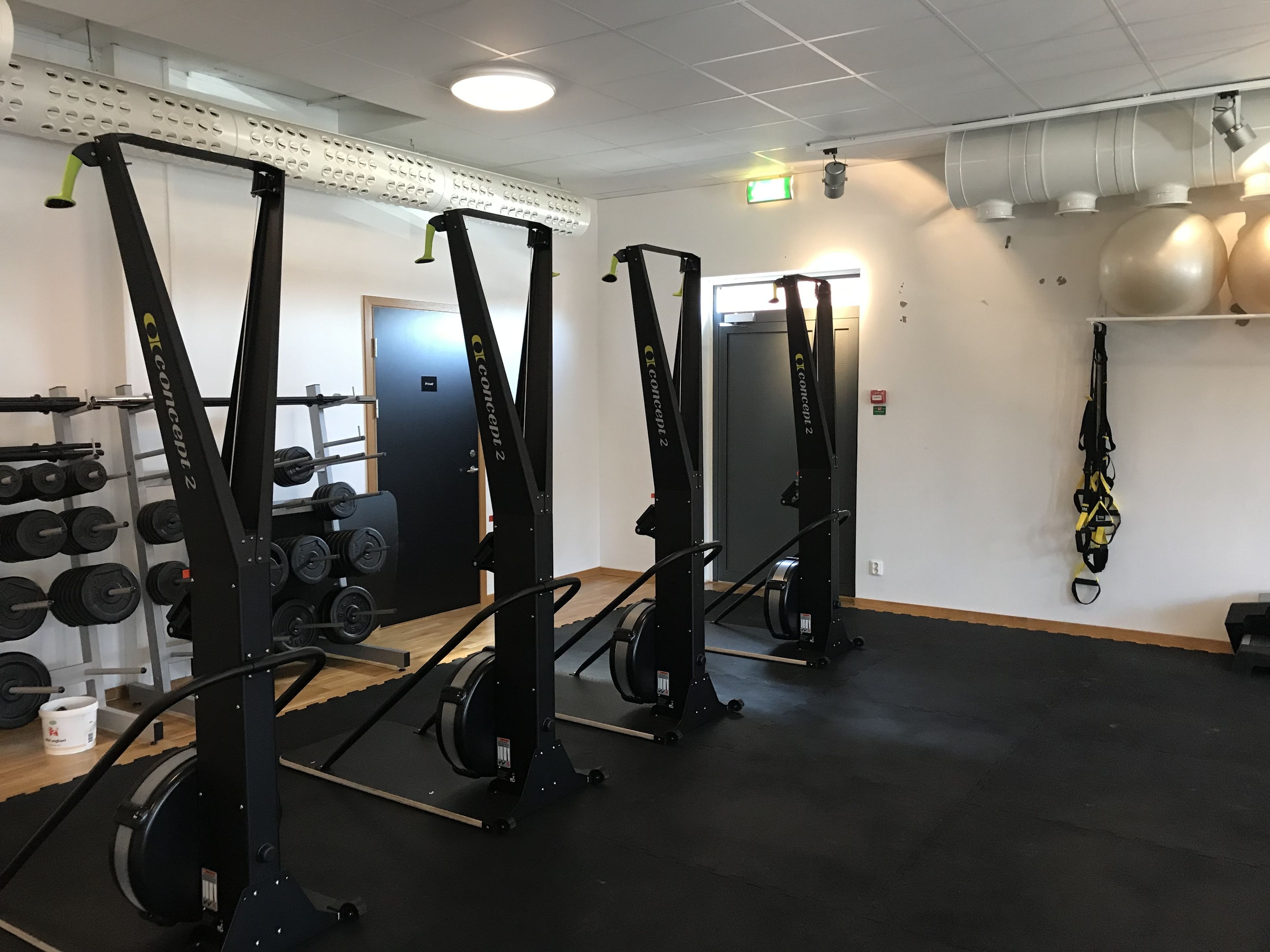 Una palestra con attrezzature per sollevamento pesi, un rastrelliera per manubri e uno specchio grande.