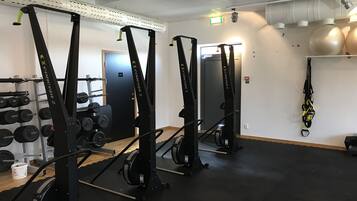 Una palestra con attrezzature per sollevamento pesi, un rastrelliera per manubri e uno specchio grande.