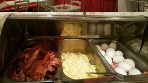A buffet area with various food options including bacon, scrambled eggs, and white eggs. - Hotell Gustaf (Götene)