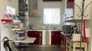 A compact kitchen with a dining area, featuring a refrigerator, microwave, and a chair. - Land / Sea / Landes- Pink Granite Coast (Perros-Guirec)