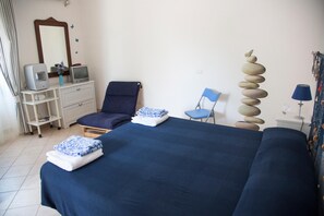 A bedroom with a bed, a chair, a desk with a computer, a mirror, and a decorative stack of stones. - La Taverna dei Ciucci Bed & Breakfast (Capaccio-Paestum)
