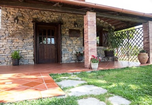 Un bâtiment en pierre avec une porte en bois, des plantes en pot et un espace patio.