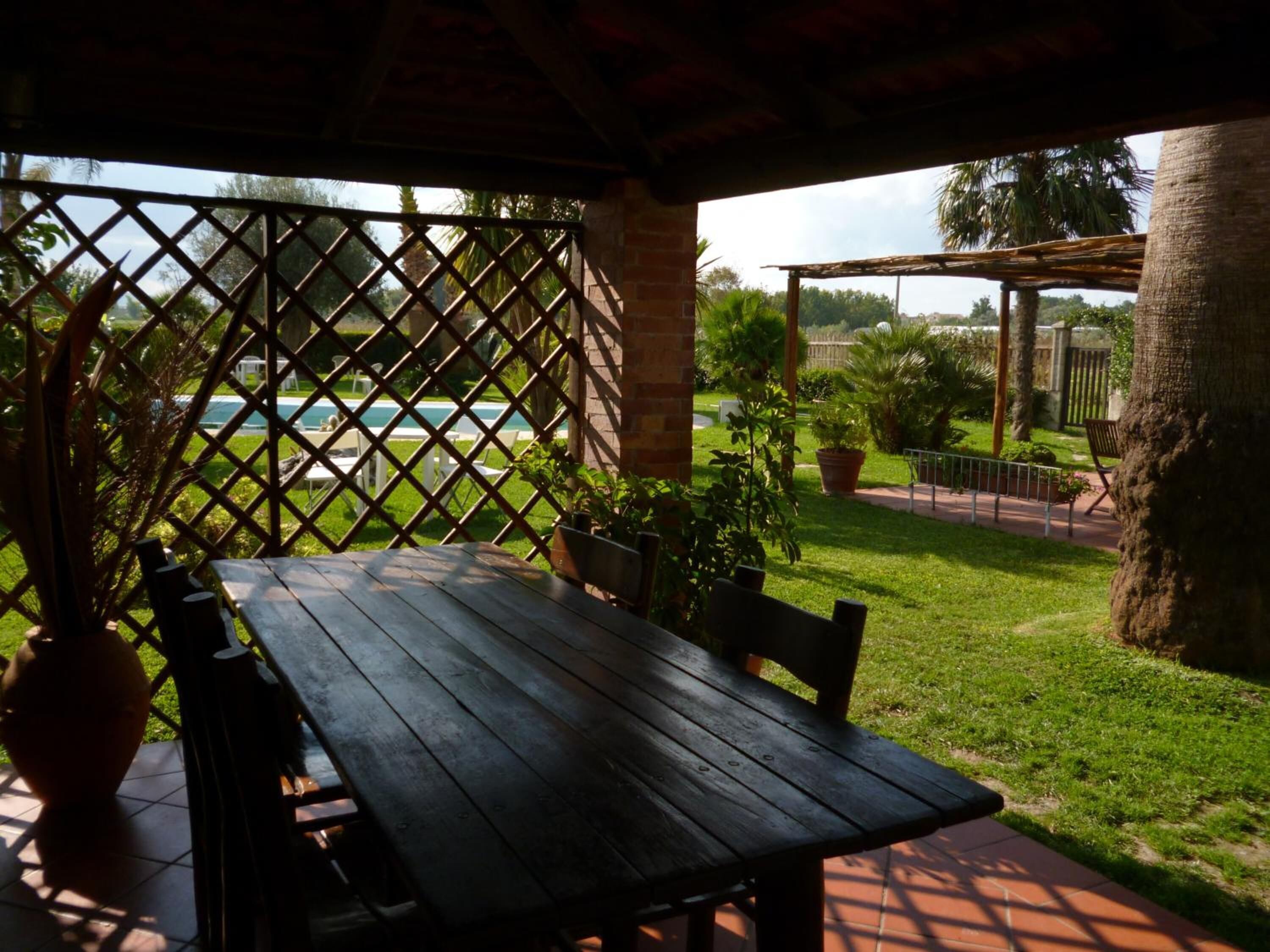 An outdoor patio with a wooden table and chairs, surrounded by a lattice fence.