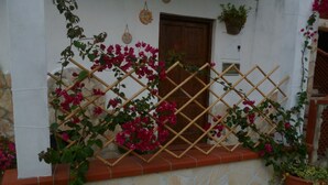 Eine Steinsäule mit einem hölzernen Gitter, das von purpurroten Bougainvillea überwuchert ist.