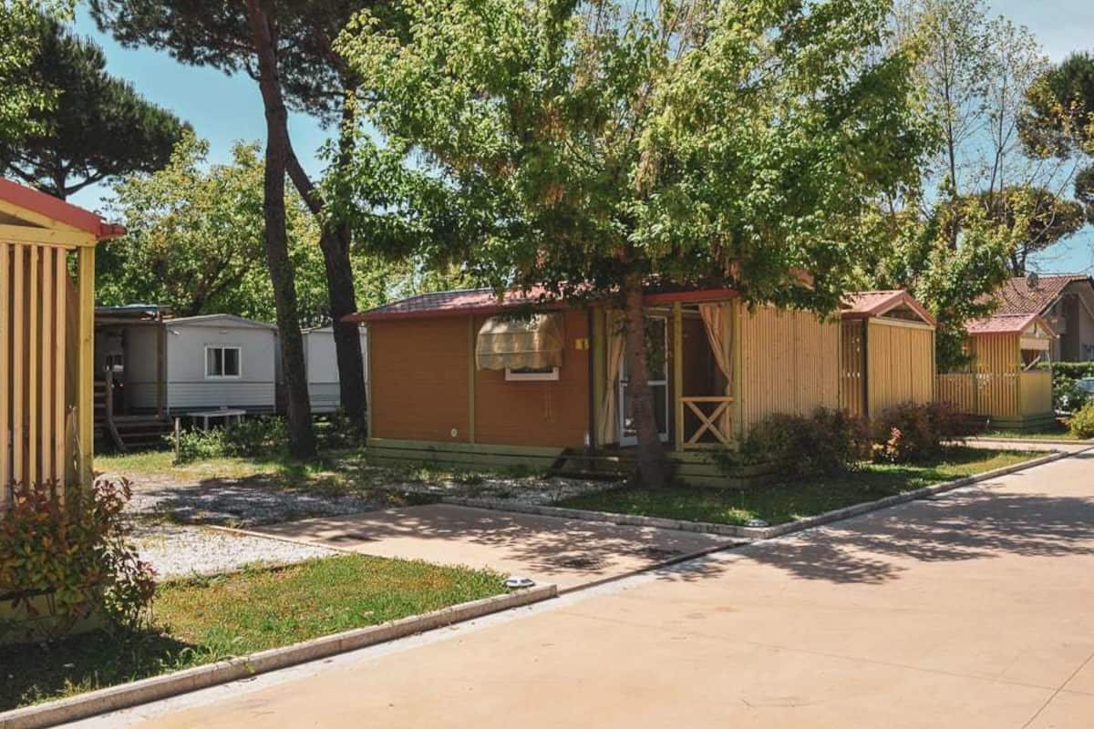 Une rangée de maisons mobiles avec une cour gazonnée et des arbres.