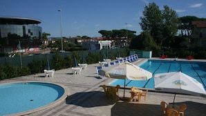 Un espace piscine comprenant plusieurs bassins, des chaises longues et des parasols.