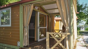 Une petite cabane en bois d’un seul étage, dotée d’une véranda, d’une porte-fenêtre coulissante et d’un petit espace extérieur.