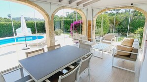 Comedor con mesa y sillas, piscina y zona de estar exterior con vistas a la vegetación.