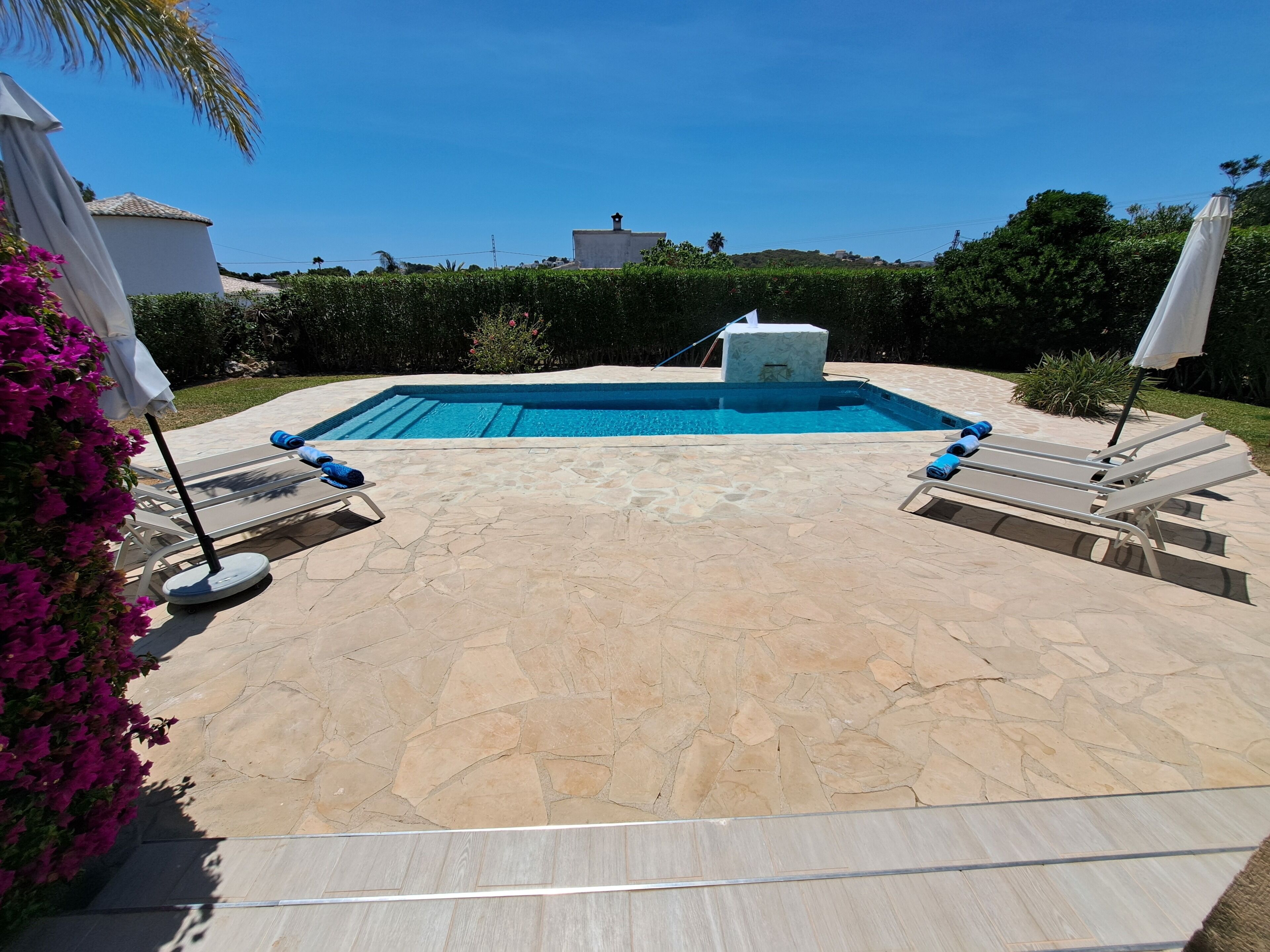 Piscina com espreguiçadeiras e um pátio de pedra.