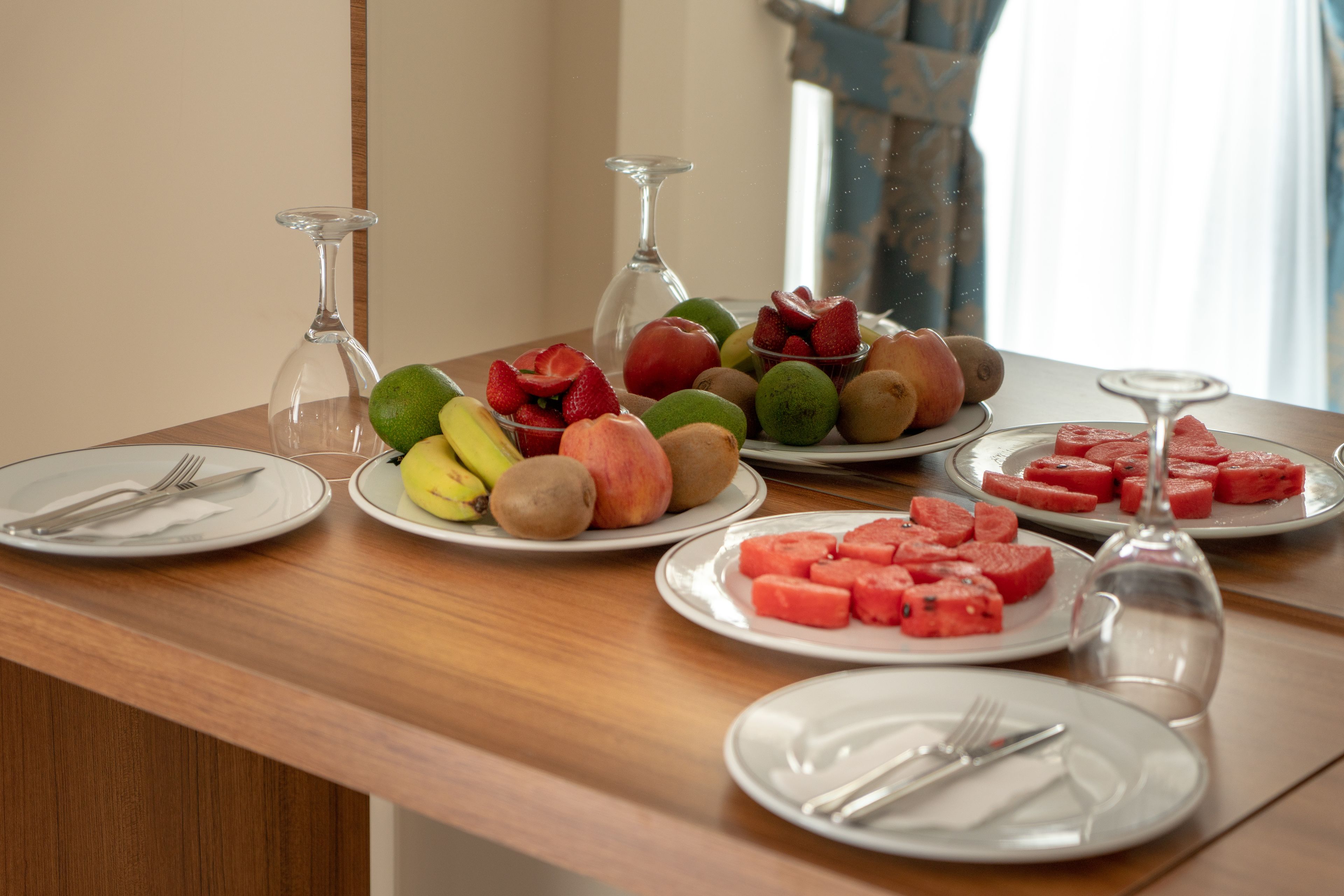 Uma mesa com pratos de fruta e copos de vinho.