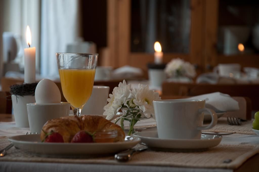 Un desayuno con cruasanes, huevos, zumo de naranja y flores sobre una mesa.