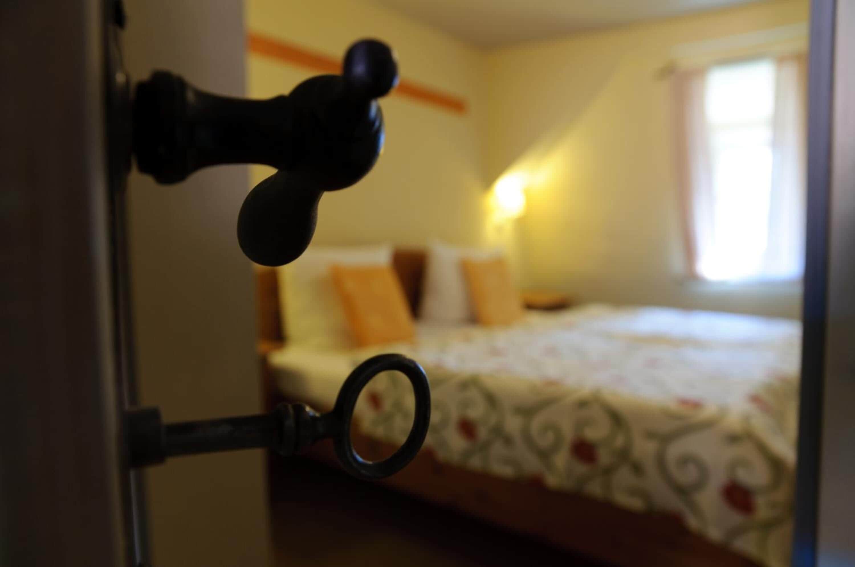 Una cerradura en una puerta, con una cama al fondo.