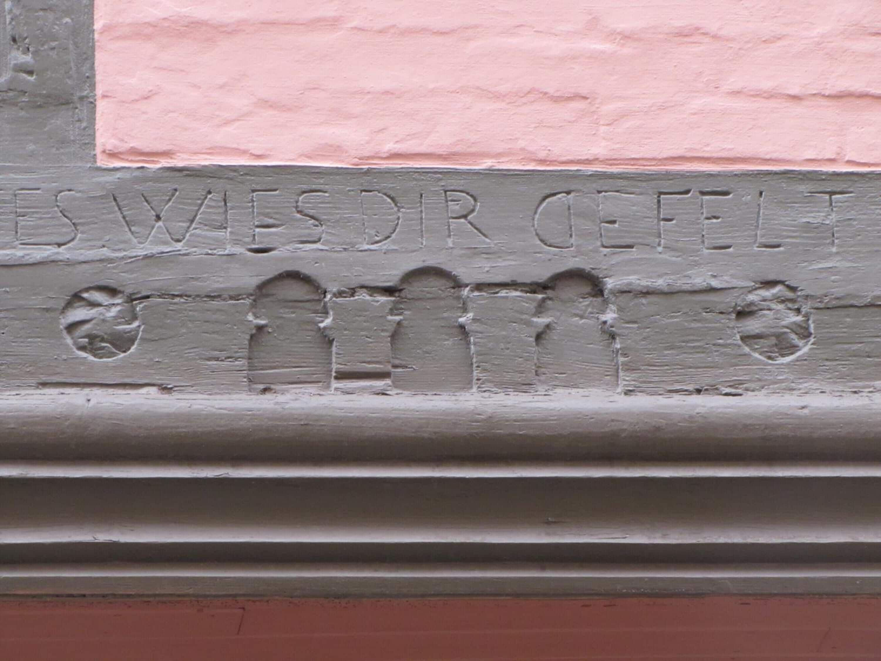 A relief sculpture with the inscription "ESWESDR OEFELT" and three circular holes.