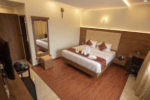 A hotel room with a large bed, a desk, a chair, and a wardrobe. - Royal Lotus View Resotel (Bengaluru)