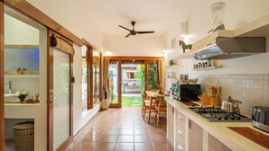 Une cuisine moderne dotée d’un îlot central, d’un coin repas et offrant une vue sur le jardin.