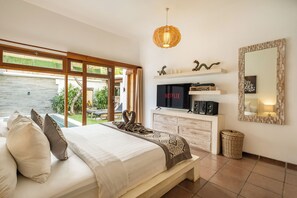 A modern bedroom with a large bed, a television, a mirror, and a view of the outdoors.