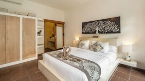 A hotel room with a large bed, a wardrobe, a mirror, a wall art piece, and a bedside table with a lamp. - Villa With Private Pool And Tropical Garden In Seminyak Bali - 2 Bedroom (Seminyak)