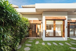 A modern house with a well-maintained garden, a dining area, and a bedroom with a large window.