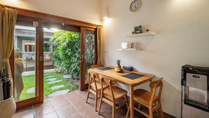 Un coin repas avec une table et des chaises en bois, un distributeur d’eau et une horloge au mur.