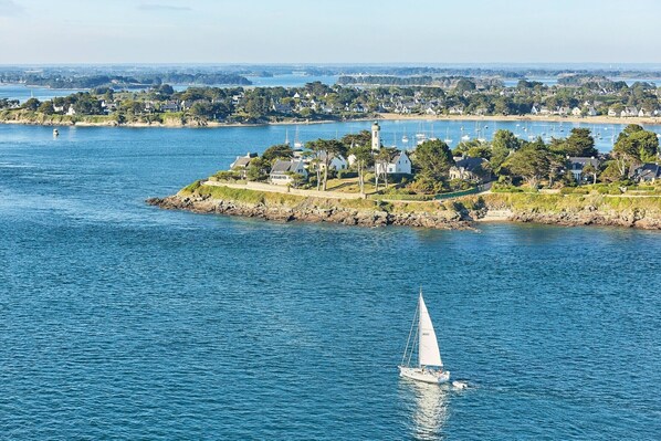 A coastal town with a lighthouse, marina, and houses along the shoreline.