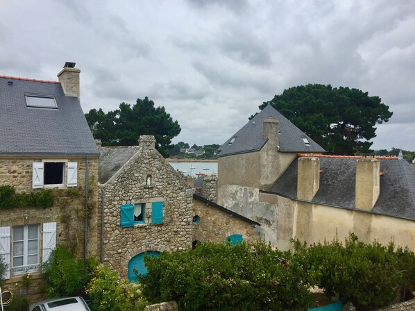 A stone building with a steep roof and a small window with blue shutters. - Character apartment between Ocean and Gulf in a charming property. (Arzon)