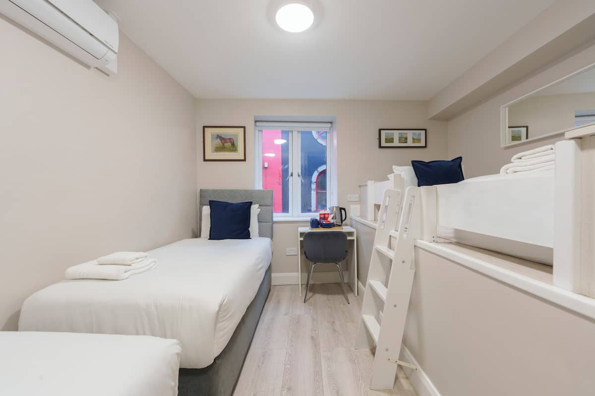 A compact hotel room with two beds, a desk, and a window.