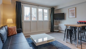 A modern living room with a sofa, a coffee table, a TV, and a dining area with chairs. - The Temple Bar Lane (Dublin)