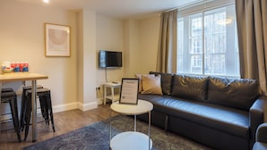 A modern living room with a sofa, a small table, a TV, and a window with curtains. - The Temple Bar Lane (Dublin)