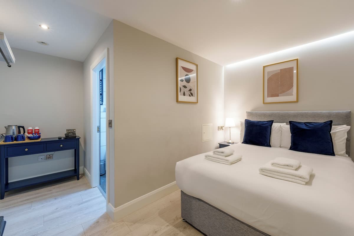 A hotel room with a bed, bedside table, and a desk with a chair.