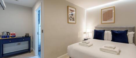 A hotel room with a bed, bedside table, and a desk with a chair.
