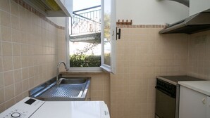 Une cuisine compacte dotée d’un lave-vaisselle encastré, d’un évier en acier inoxydable et d’un petit four.